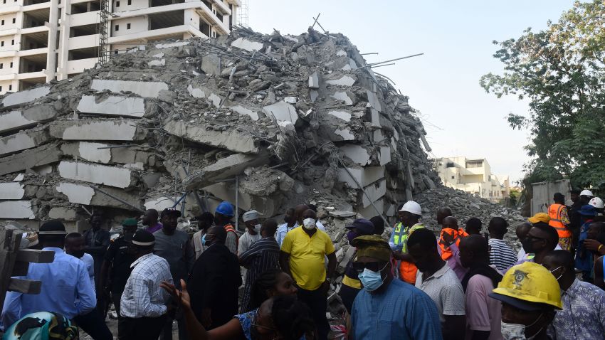 TOPSHOT - People stand to look at the rubble of a 21-storey building under construction that collapsed in the Ikoyi district of Lagos, on November 1, 2021. - Several people have been trapped while unspecified number of people mostly construction workers were feared dead as a 21-storey building suddenly collapsed in the Ikoyi district of Lagos, Nigeria's commercial capital. (Photo by PIUS UTOMI EKPEI / AFP) (Photo by PIUS UTOMI EKPEI/AFP via Getty Images)