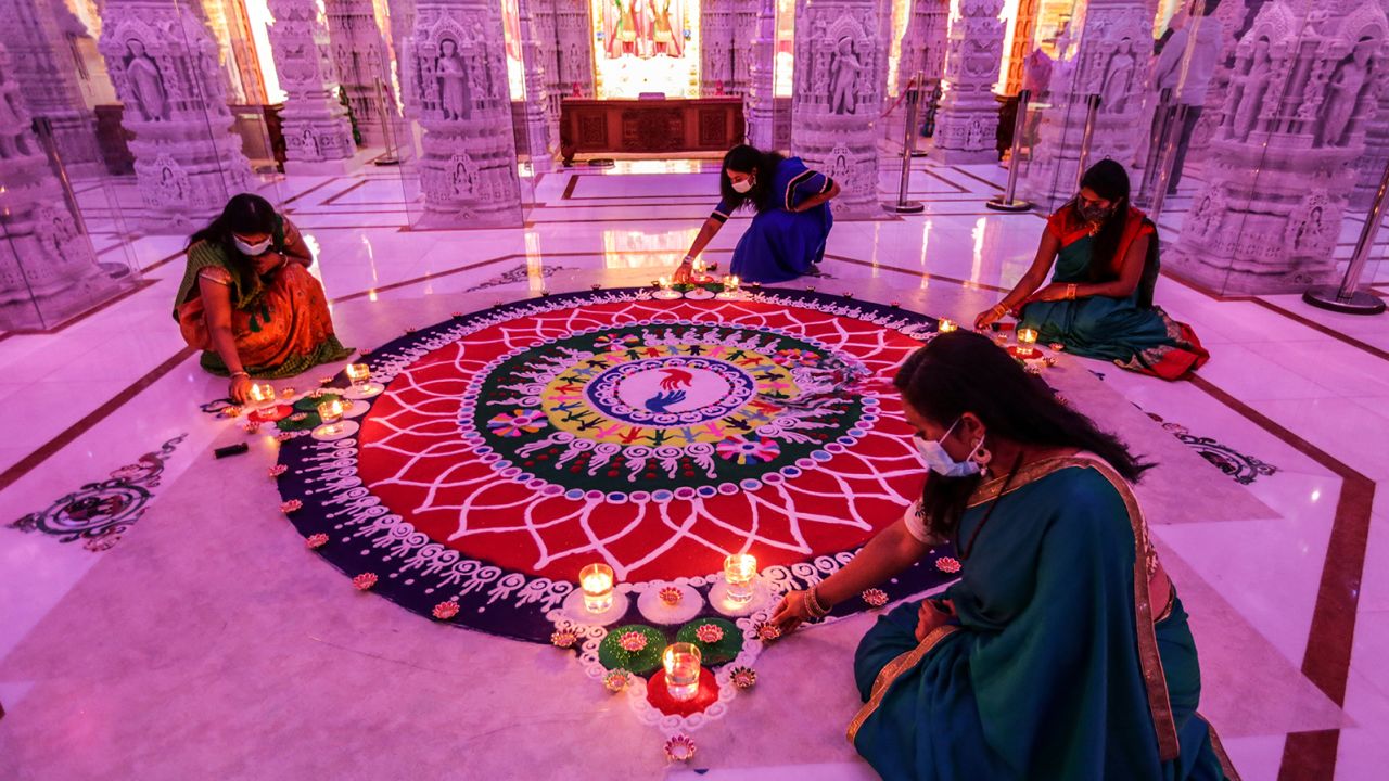 Women tend to a rangoli, a geometric pattern typically created using colored sand, during a Diwali celebration in Chino Hills, California, in 2020.