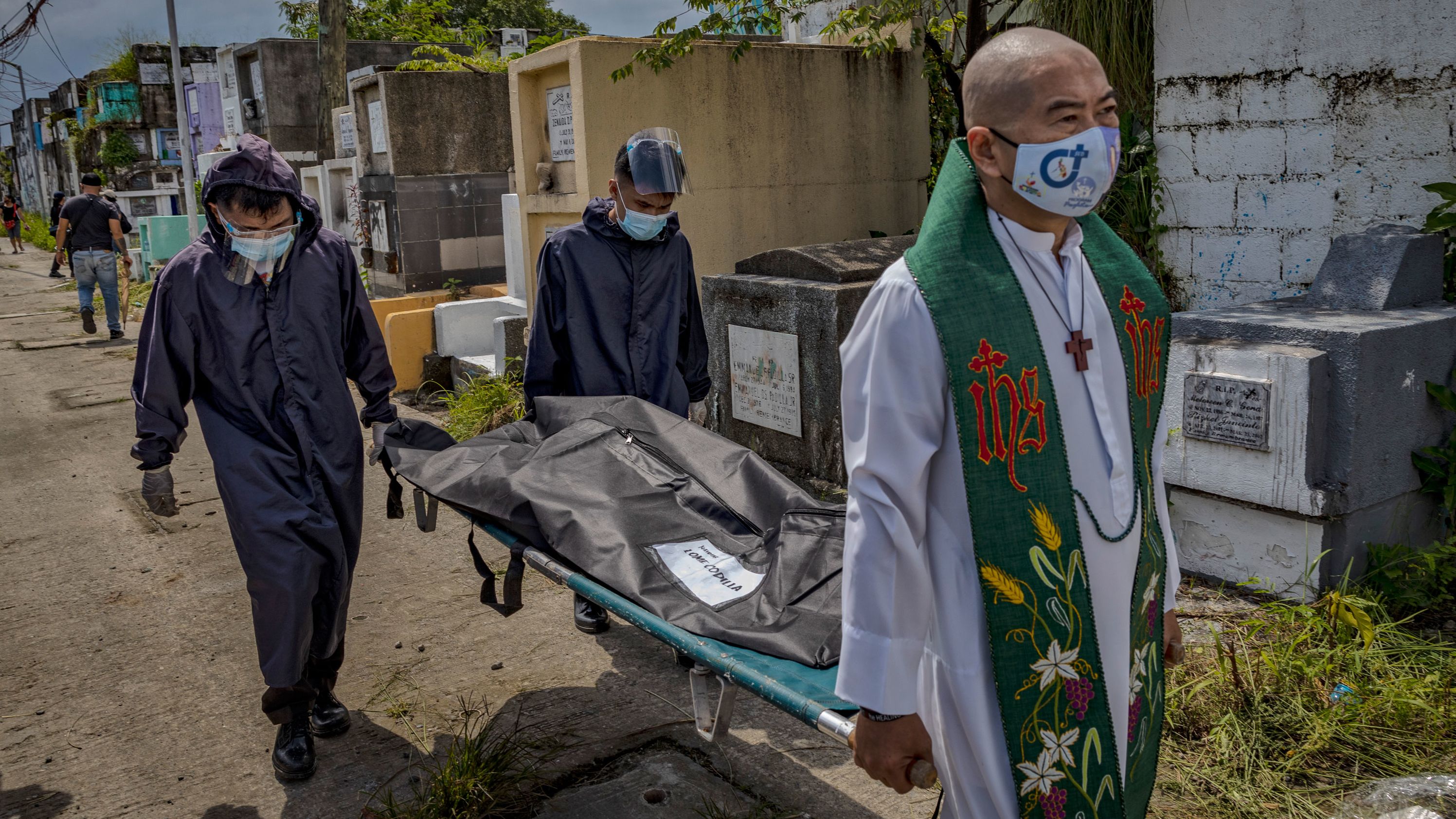 A  priest carries a body bag containing the remains of a victim of an alleged extrajudicial killing five years ago, which was exhumed after the lease on his tomb expired at a public cemetery on September 17 in Navotas, Metro Manila, Philippines.