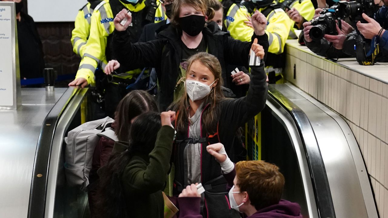 Thunberg gestures to cameras and supporters after arriving in Glasgow on Saturday ahead of the COP26 summit. 