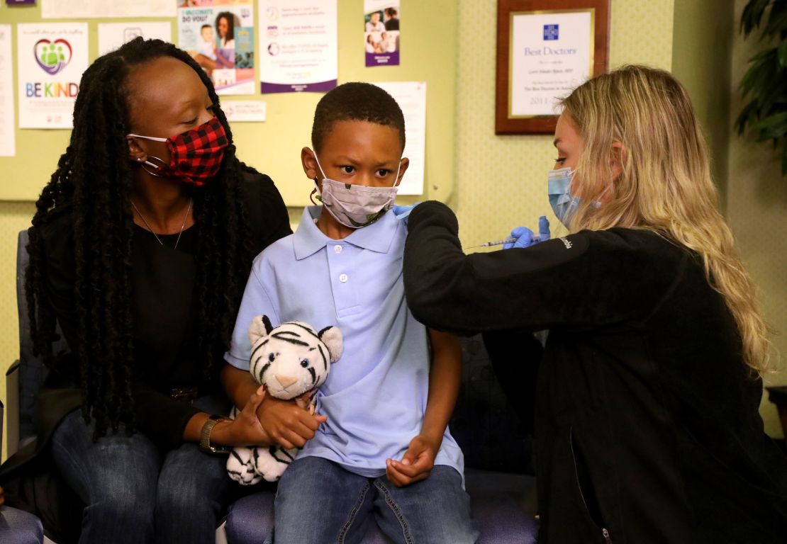 Tyann Davis holds her son Cameron Davis' hand as IHA Plymouth Pediatrics Medical Assistant Madison Peterson gives him the Pfizer Covid vaccine.