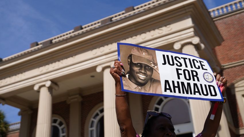BRUNSWICK, GA - OCTOBER 18: A demonstrator holds a sign at the Glynn County Courthouse as jury selection begins in the trial of the shooting death of Ahmaud Arbery on October 18, 2021 in Brunswick, Georgia. Three white men are accused of chasing down and murdering Arbery in southeastern Georgia last year. (Photo by Sean Rayford/Getty Images)