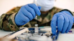 A member of the National Guard prepares a dose of the Pfizer-BioNTech Covid-19 vaccine at the University of New Orleans Lakefront Arena drive-thru facility in New Orleans, Louisiana, U.S., on Tuesday, Aug. 24, 2021. The Louisiana Department of Health reported an increase in confirmed Covid-19 cases by 8,296 on Monday. 