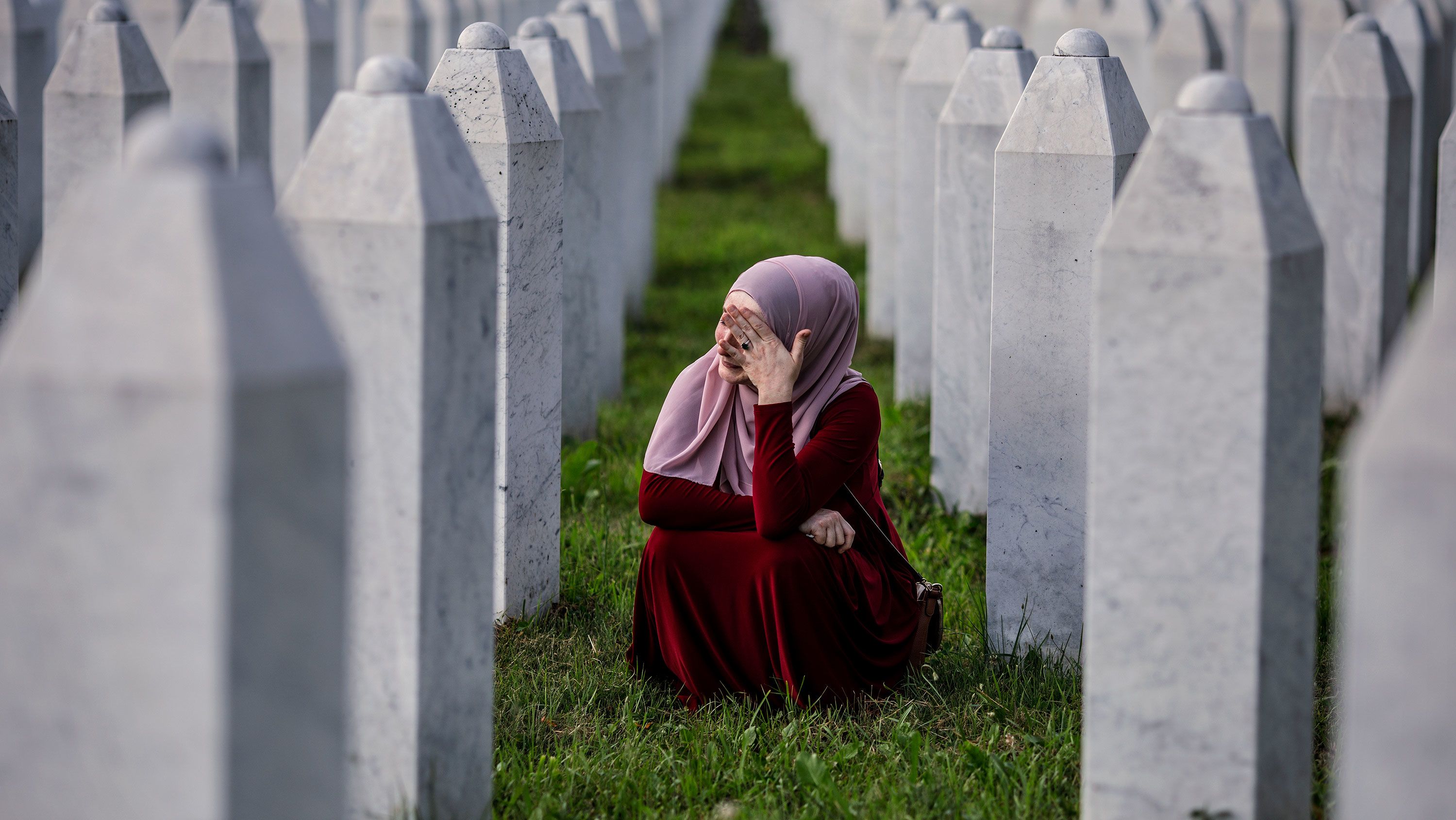 A Bosnian Muslim woman cries between graves of her father, two grandfathers and other close relatives, all victims of the 1995 Srebrenica genocide, in July 2020. 