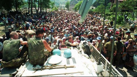 Dutch UN peacekeepers sit on top of a vehicle while Muslim refugees from Srebrenica gather in the nearby village of Potocari on July 13, 1995. 