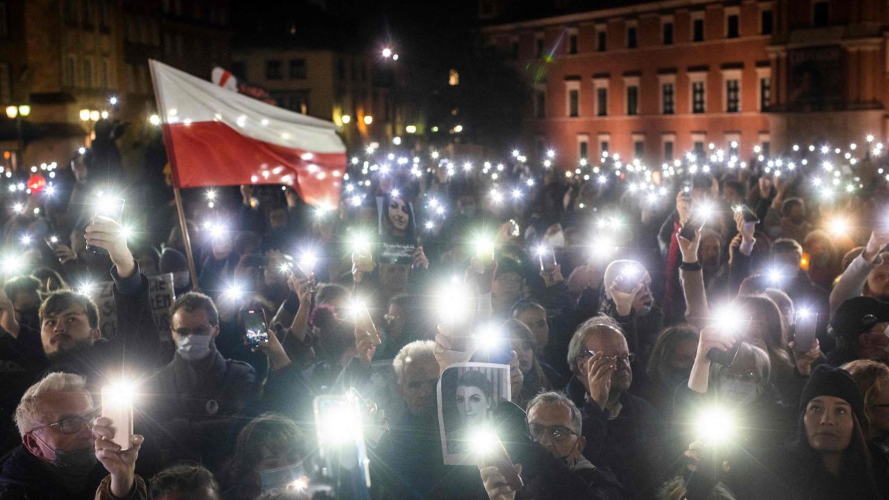 Protesters hold up lights, a Polish flag and a photograph of Iza as they take part in a demonstration on November 6, 2021 in Warsaw.