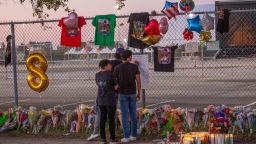 Seventeen years old local high School friends who attended the Travis Scott concert, Isaac Hernandez and Matthias Coronel watch Jesus Martinez sign a remembrance board at a makeshift memorial on November 7, 2021 at the NRG Park grounds where eight people died in a crowd surge at the Astroworld Festival in Houston, Texas.
