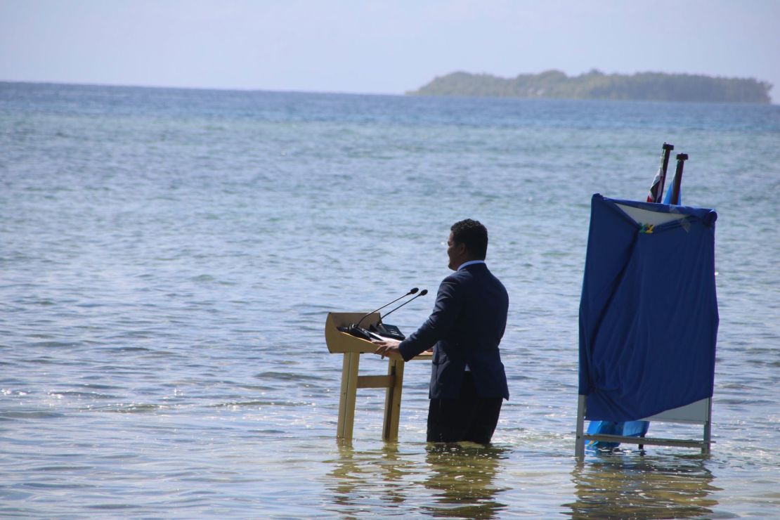 Tuvalu's foreign minister stands knee-deep in seawater to highlight how climate change is leading to a rise in sea levels.