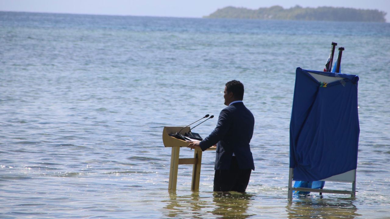 Tuvalu's foreign minister stands knee-deep in seawater to highlight how climate change is leading to a rise in sea levels.