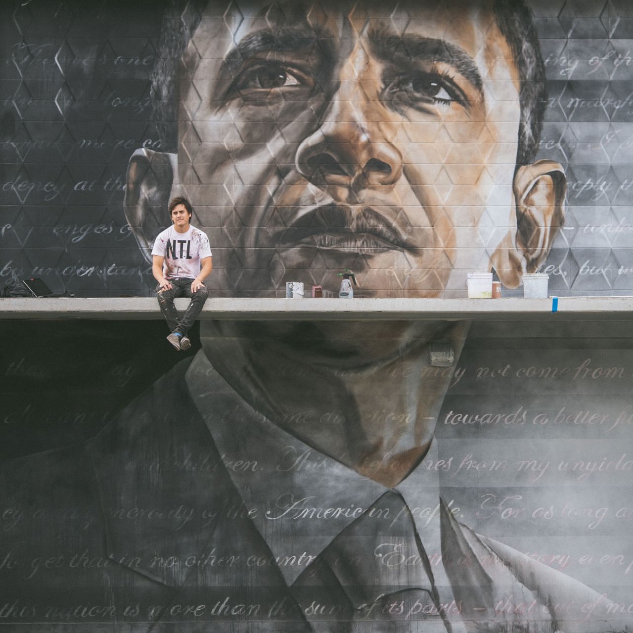 Kamea Hadar sitting in front of his Obama mural. 