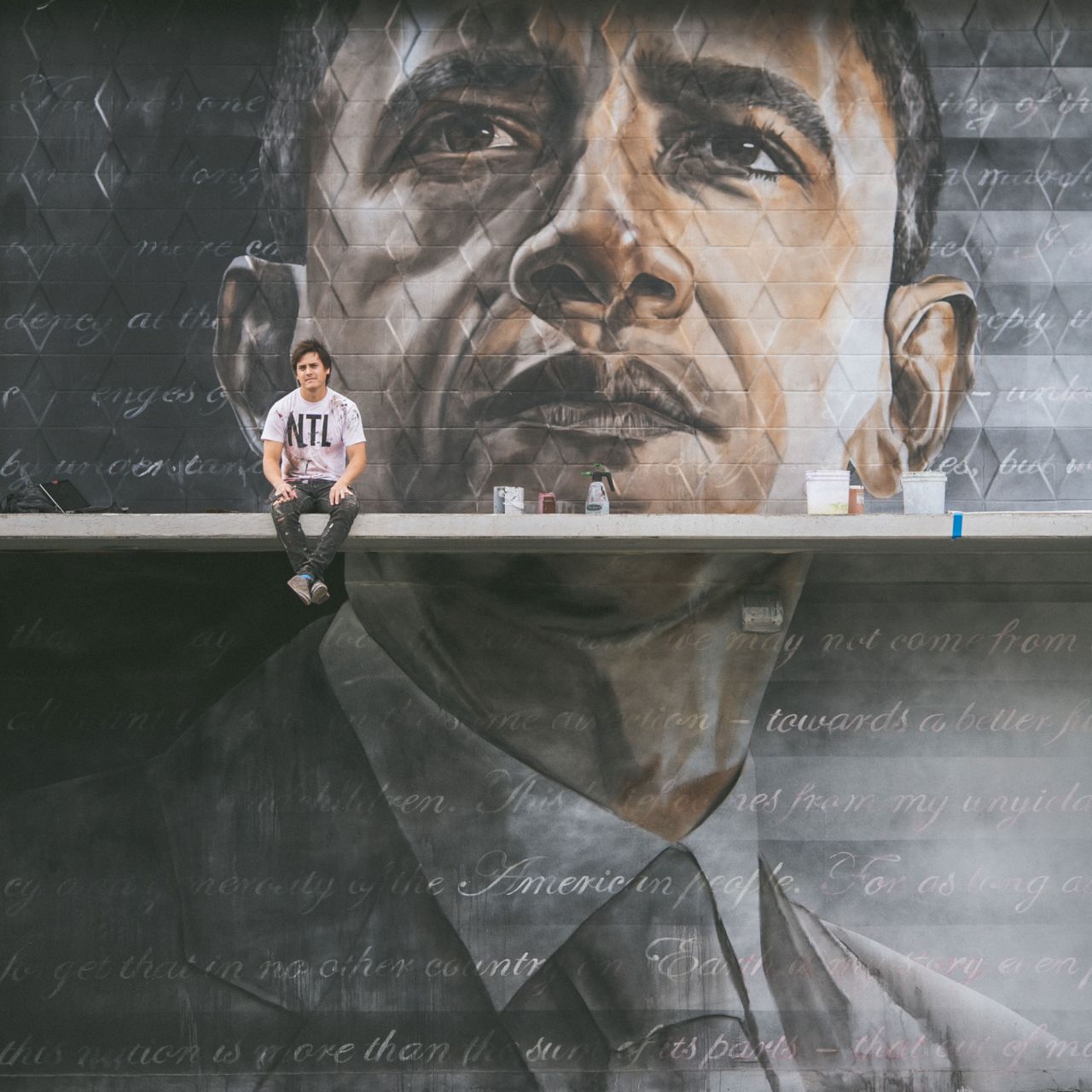 Kamea Hadar sitting in front of his Obama mural.