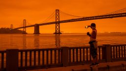 SAN FRANCISCO, CA - SEPTEMBER 09: Amy Scott of San Francisco takes in the view from the Embarcadero as smoke from various wildfires burning across Northern California mixes with the marine layer, blanketing San Francisco in darkness and an orange glow on September 9, 2020 in San Francisco, California.  Over 2 million acres have burned this year as wildfires continue to burn across the state. (Photo by Philip Pacheco/Getty Images)