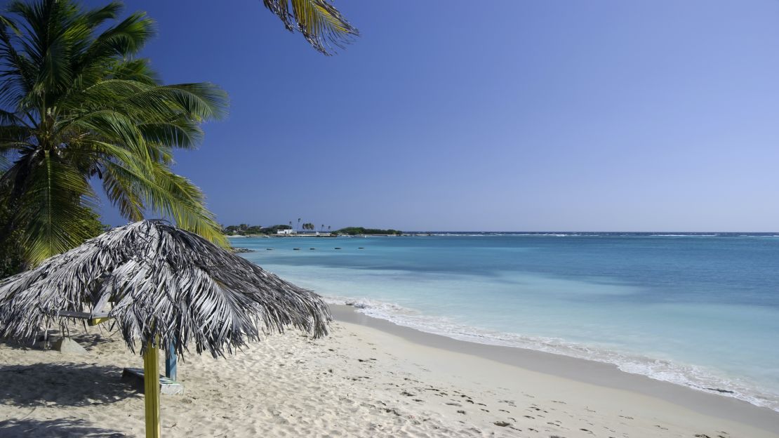 An empty tropical beach in the Caribbean.  Wide shot with clear, blue sky and plenty of room for copy.