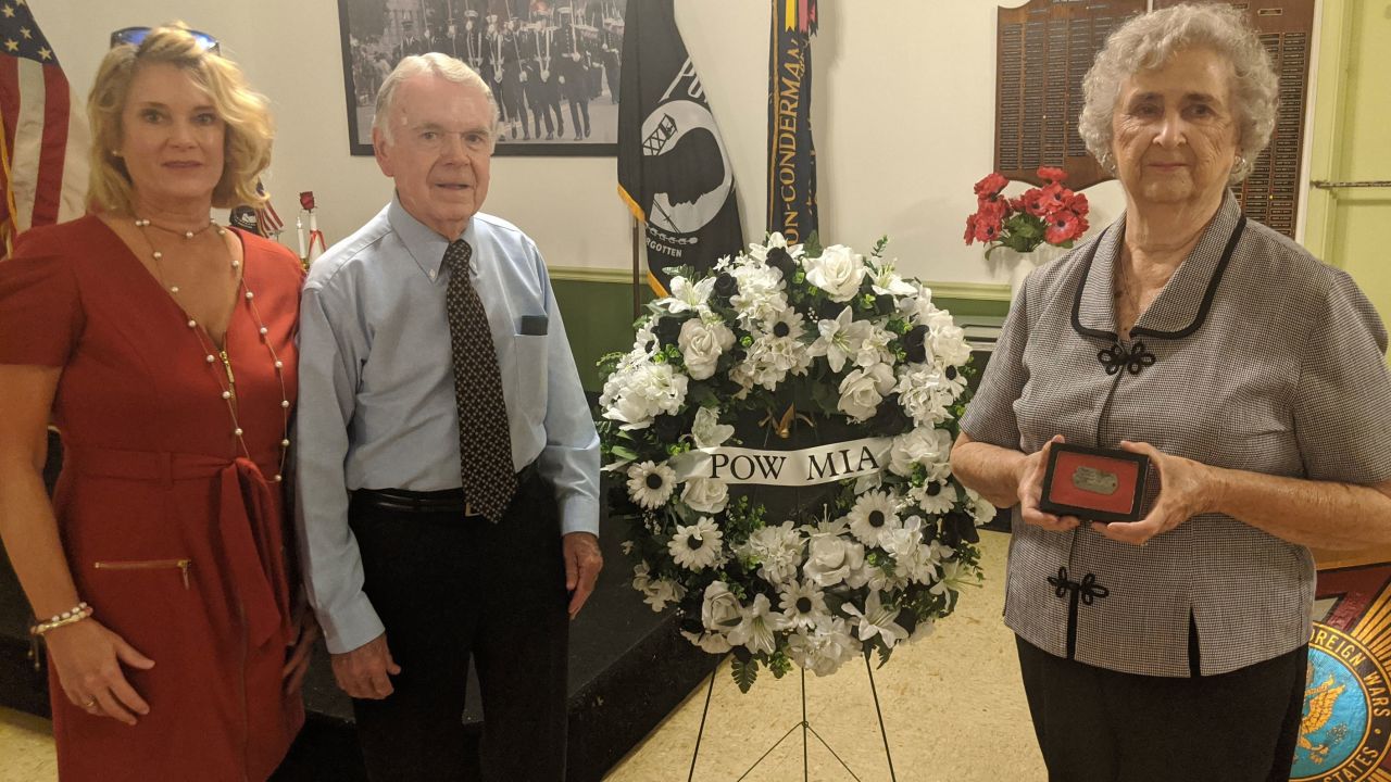 Marian Cook Haddock holds her uncle's dog tag at the September ceremony with her daughter, Mary Margaret, and husband, John.