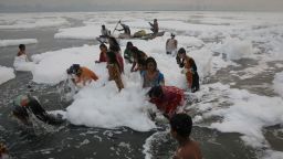 People bathe amidst toxic foam covering the Yamuna river on a smoggy morning in New Delhi, India November 8, 2021. REUTERS/Anushree Fadnavis
