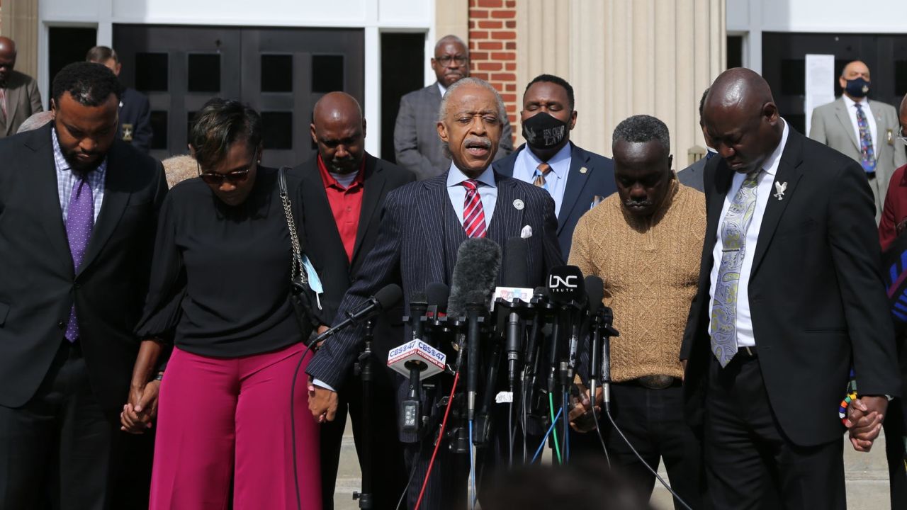 Rev. Al Sharpton, center, holds hands with Ahmaud Arbery's parents Wanda Cooper-Jones and Marcus Arbery as they pray together on Wednesday in front of the Glynn County Courthouse.