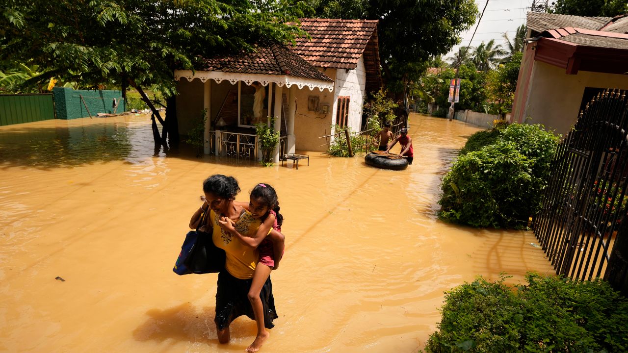 A woman and child wade through a flooded area in Kochchikade,  Sri Lanka on November 10, 2021. 