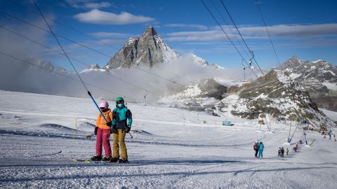 Skiers wearing protective face masks ride a ski lift before hitting the slopes with the Matterhorn mountain as landscape above the ski resort of Zermatt in the Swiss Alps on November 28, 2020. - In non-EU Switzerland, which has been hard-hit by the second wave of Covid-19, the authorities, ski and tourism sectors have stood united behind the decision to keep the winter season going as EU countries debate a bloc-wide ban on ski holidays to curb coronavirus infections. "In Switzerland, we can go skiing, with protection plans in place," Swiss Health Minister Alain Berset told reporters on November 26, 2020. (Photo by Fabrice COFFRINI / AFP) (Photo by FABRICE COFFRINI/AFP via Getty Images)