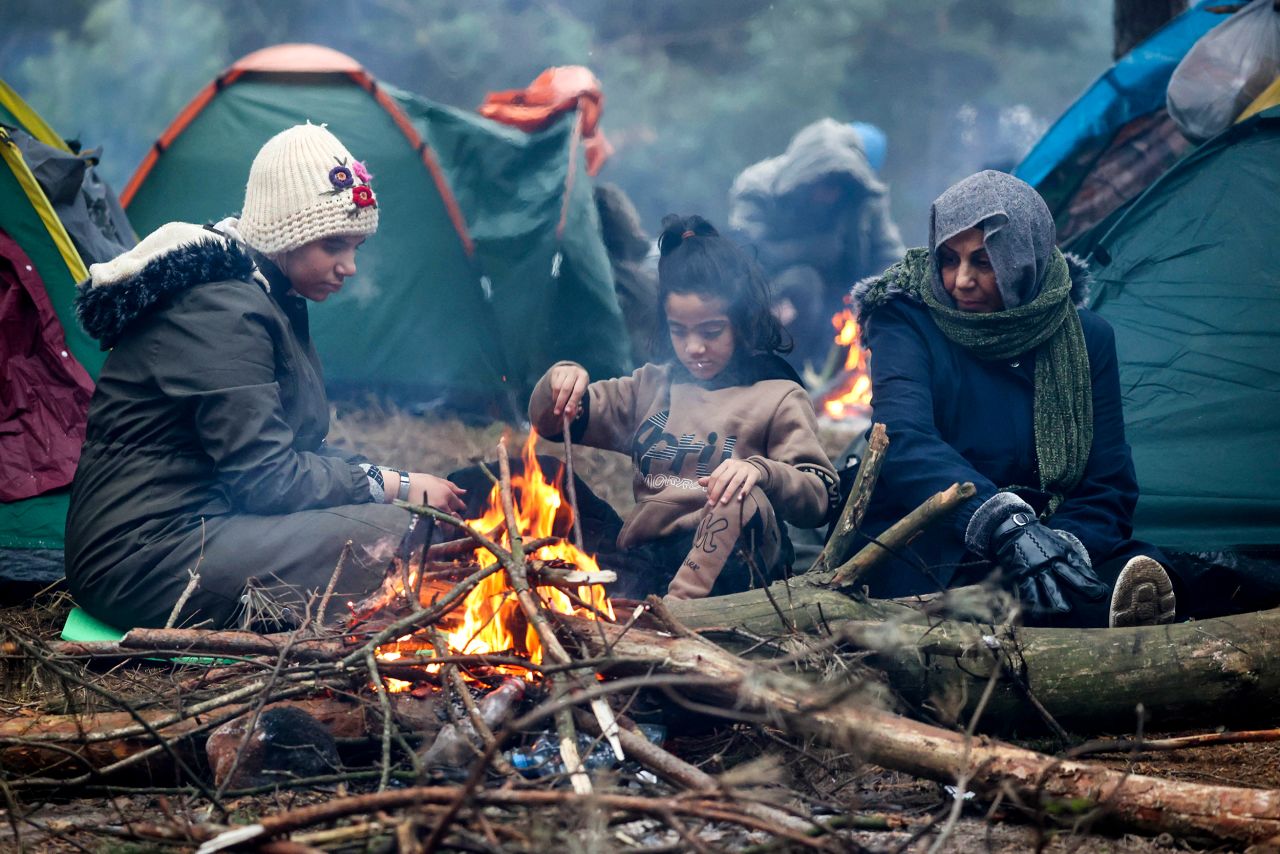 Migrants warm themselves by a fire on Wednesday, November 10.