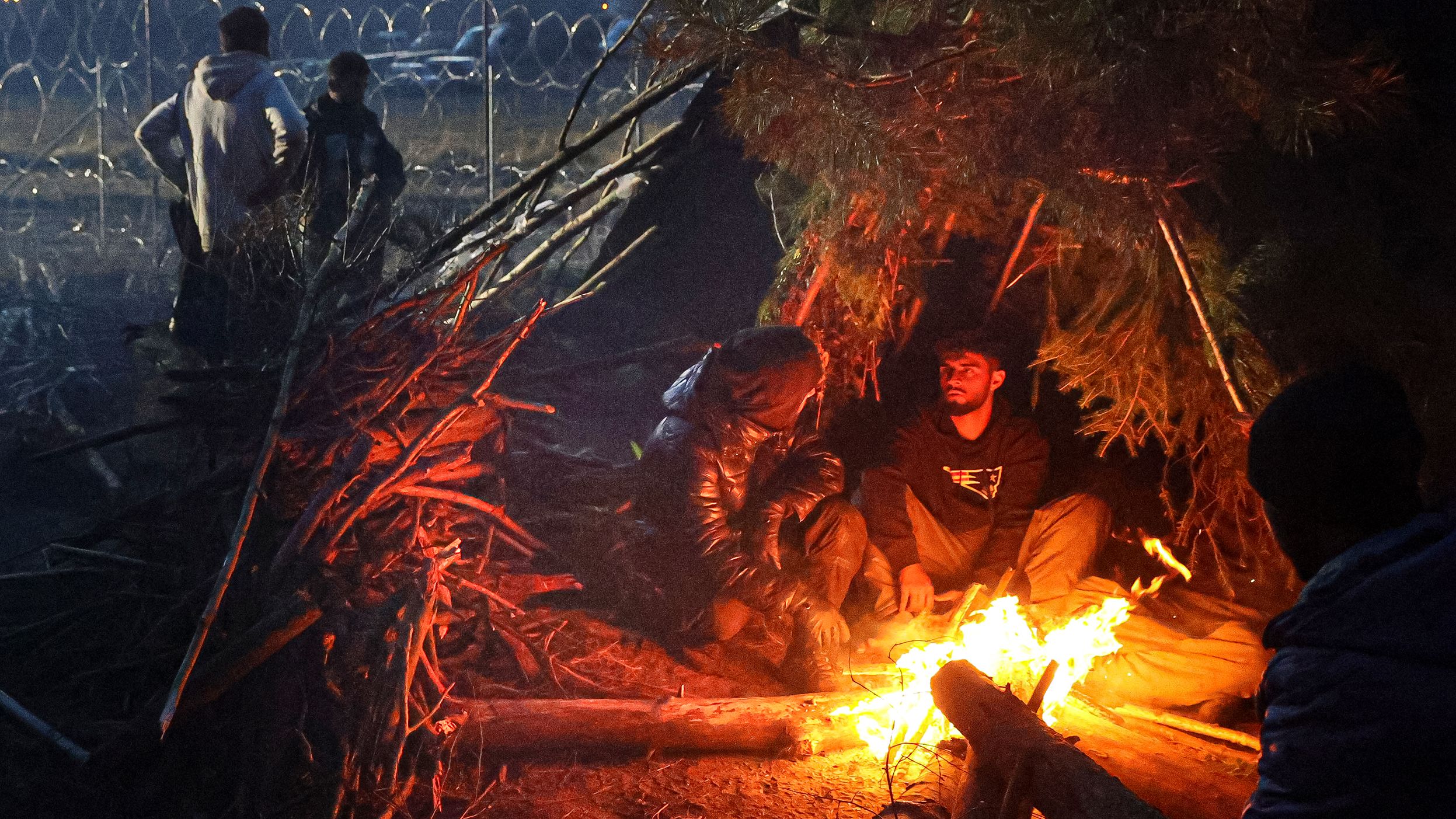 Migrants rest near a fire near the border on Wednesday, November 10.
