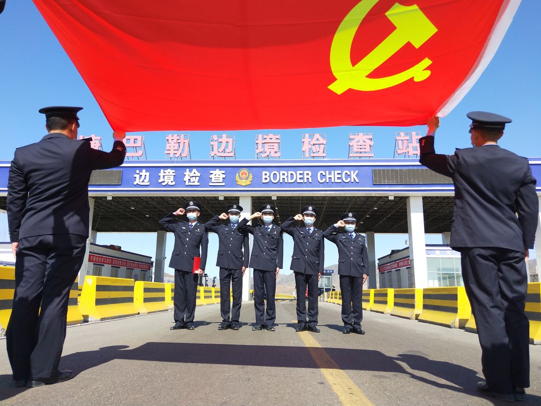 Police officers salute the flag of the Chinese Communist Party at a border inspection station on May 7, 2021, in Altay prefecture, Xinjiang.
