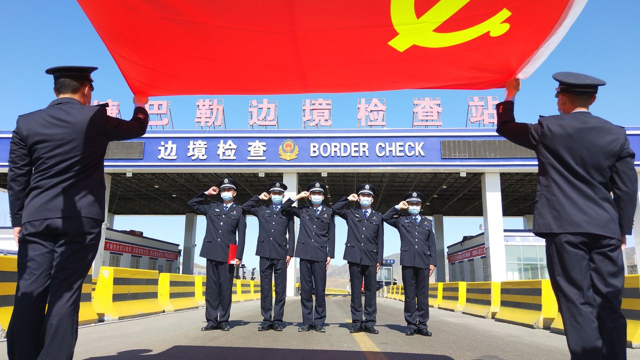 Police officers salute the flag of the Chinese Communist Party at a border inspection station on May 7, 2021, in Altay prefecture, Xinjiang.