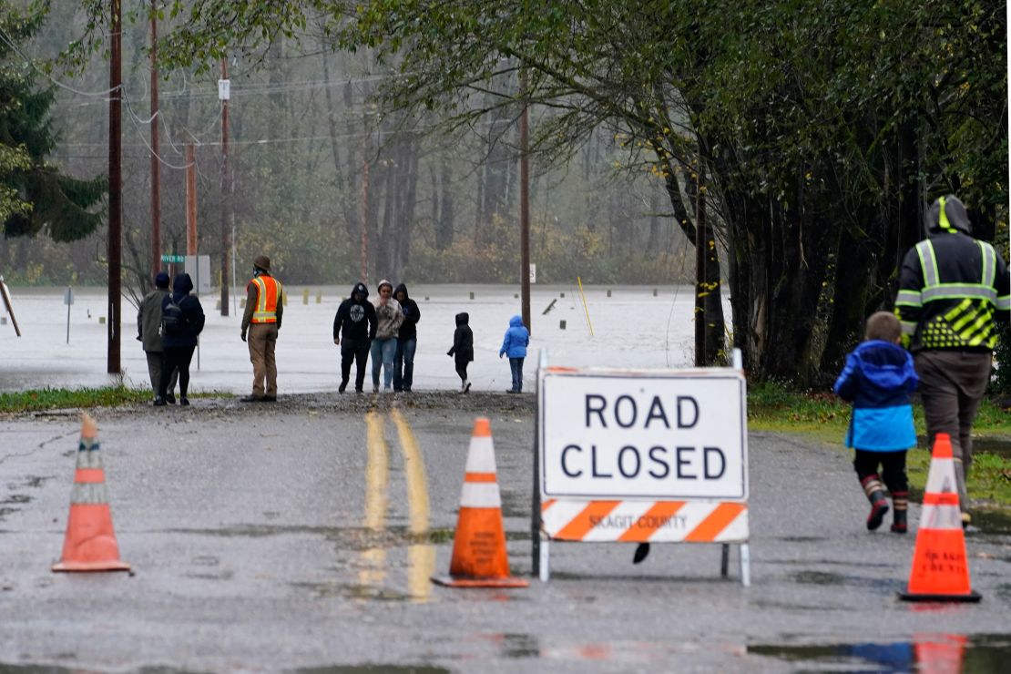 People in Sedro-Woolley, Washington, walk up to a roadway flooded Monday by the overflowing Skagit River.