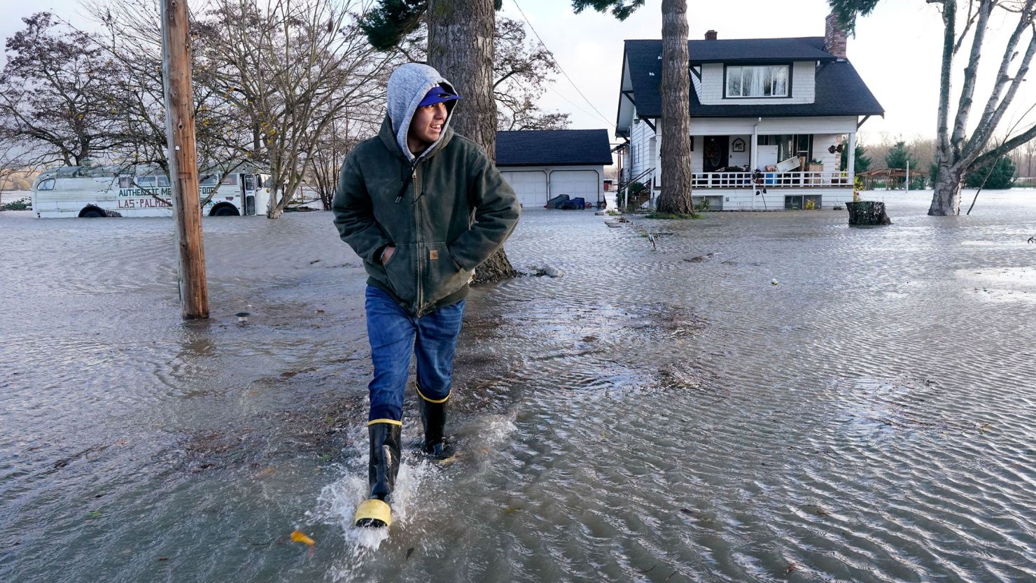 Benjamin Lopez steps from floodwater surrounding his parents home Monday in Sedro-Woolley, Washington.