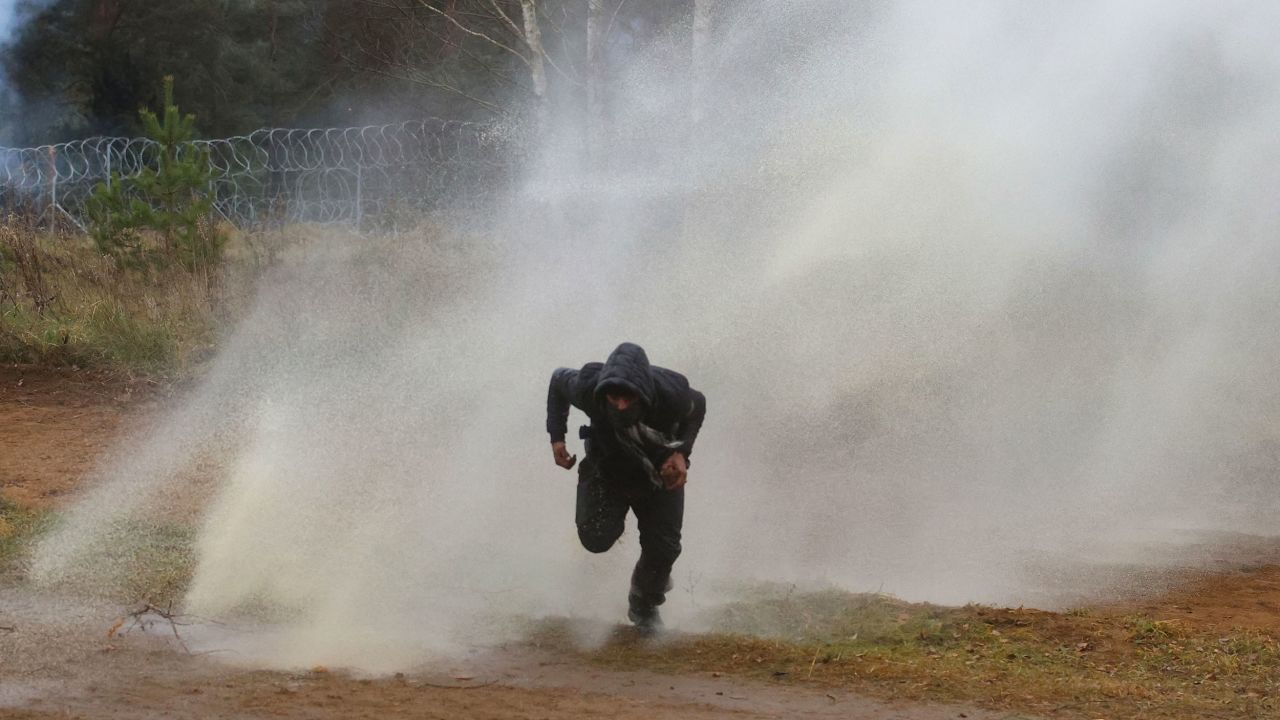 A man runs away from water cannon fired by Polish officers at the Bruzgi-Kuźnica border crossing.