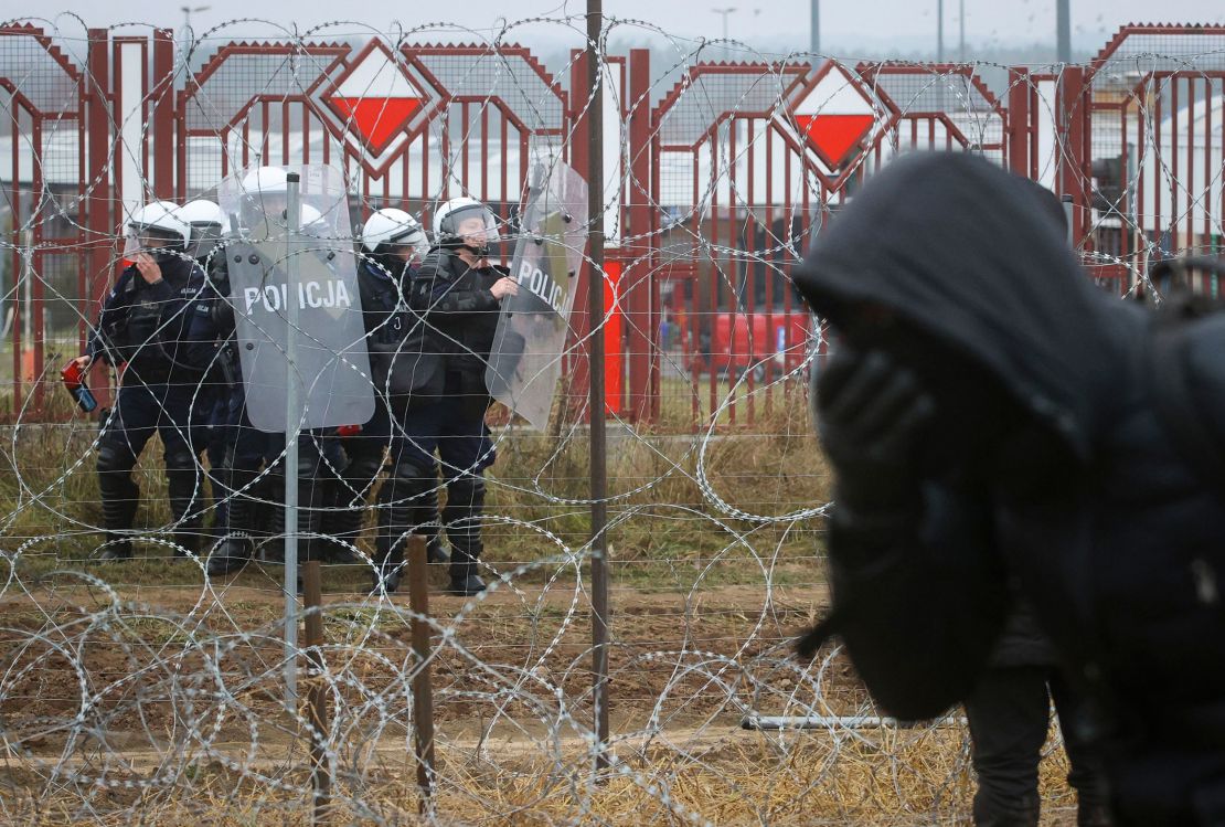 Polish servicemen are seen on the other side of barbed wire during clashes between migrants and Polish border guards at the Belarus-Poland border near Grodno, Belarus, on Tuesday, Nov. 16, 2021.