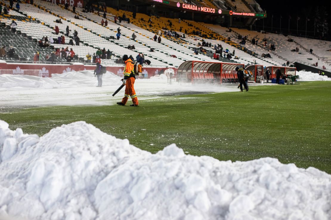 Crews clean snow off the pitch before the match in Edmonton.