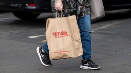 A shopper wearing protective gloves holds a shopping bag outside of a T.J. Maxx store in Alameda, California, U.S., on Monday, May 17, 2021. 