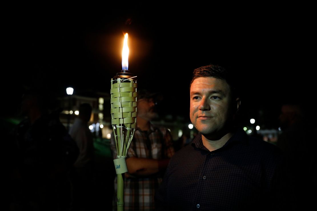 Jason Kessler, the organizer of Unite the Right, stands beside a torch before the march the night ahead of the rally.