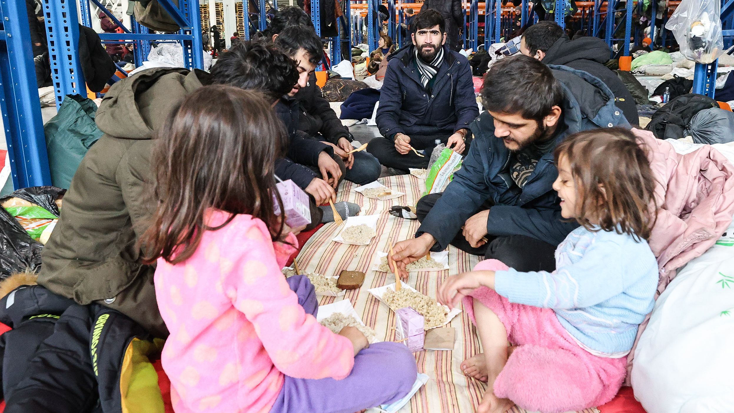 Migrants get a hot meal near the Bruzgi checkpoint on the Polish border on Tuesday, November 17, after a shelter was set up in a warehouse.