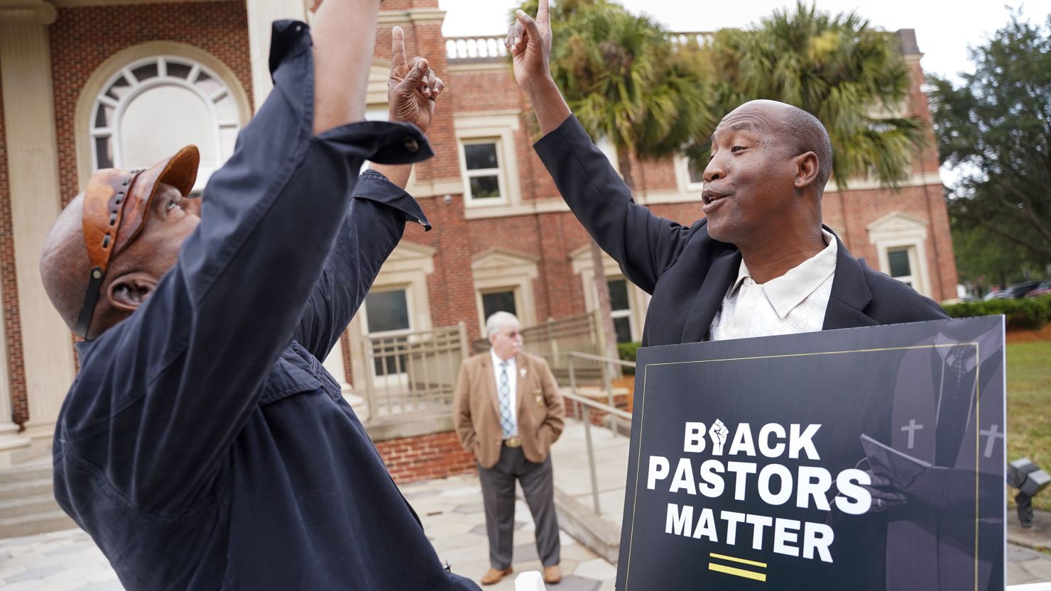 Rev. Siegfried Darcell White, right, points to the sky Thursday at the Glynn County Courthouse in Brunswick, Georgia, before a court session in the trial of the men accused of killing Ahmaud Arbery.