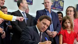 Florida Gov. Ron DeSantis, seated, signs a bill in front of supporters and members of the media during a news conference Thursday, Nov. 18, 2021, in Brandon, Fla. DeSantis signed the bill that protects employees and their families from coronavirus vaccine and mask mandates. (AP Photo/Chris O'Meara)