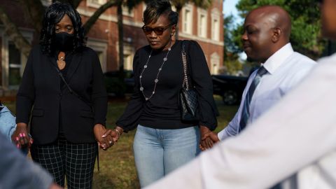 Ahmaud Arbery's mother, Wanda Cooper-Jones, holds hands with her sister Linda Ellison, left, while being led in prayer outside the Glynn County Courthouse.