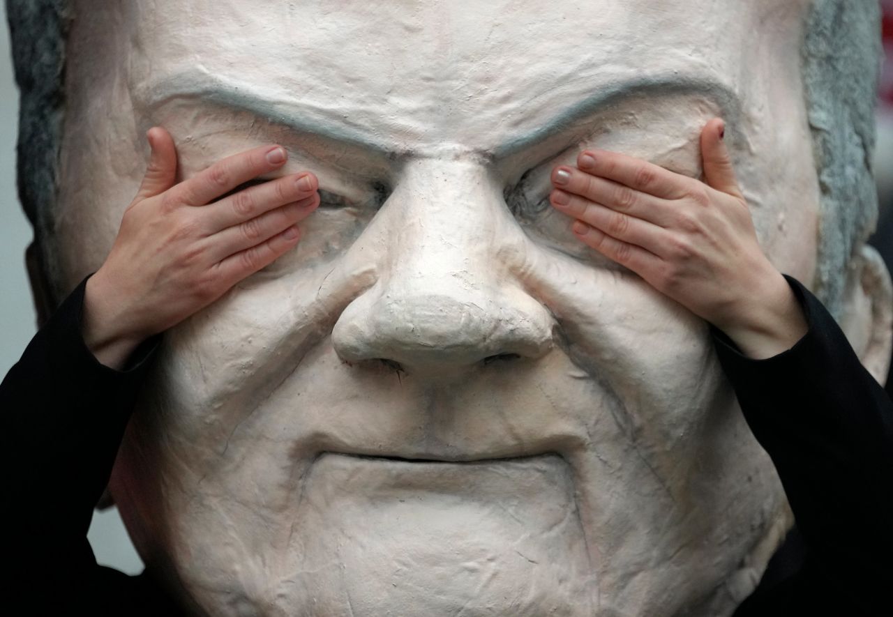 A protester in Berlin poses with a mask of German Vice-Chancellor <a href="https://www.cnn.com/2021/09/27/europe/olaf-scholz-profile-spd-germany-election-intl/index.html" target="_blank">Olaf Scholz</a> on Monday, November 15.