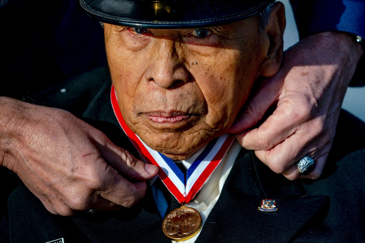 A man adjusts the Congressional Gold Medal on World War II veteran Remigio "Rey" Cabacar at a Veterans Day ceremony in Washington, DC., on Thursday, November 11.