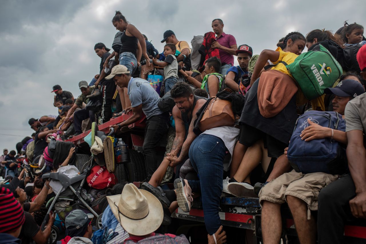 Migrants help one another onto the bed of a trailer in Jesús Carranza, Mexico, on Wednesday, November 17. The migrant group, which mainly consists of people from Central America, is trying to reach the US-Mexico border.