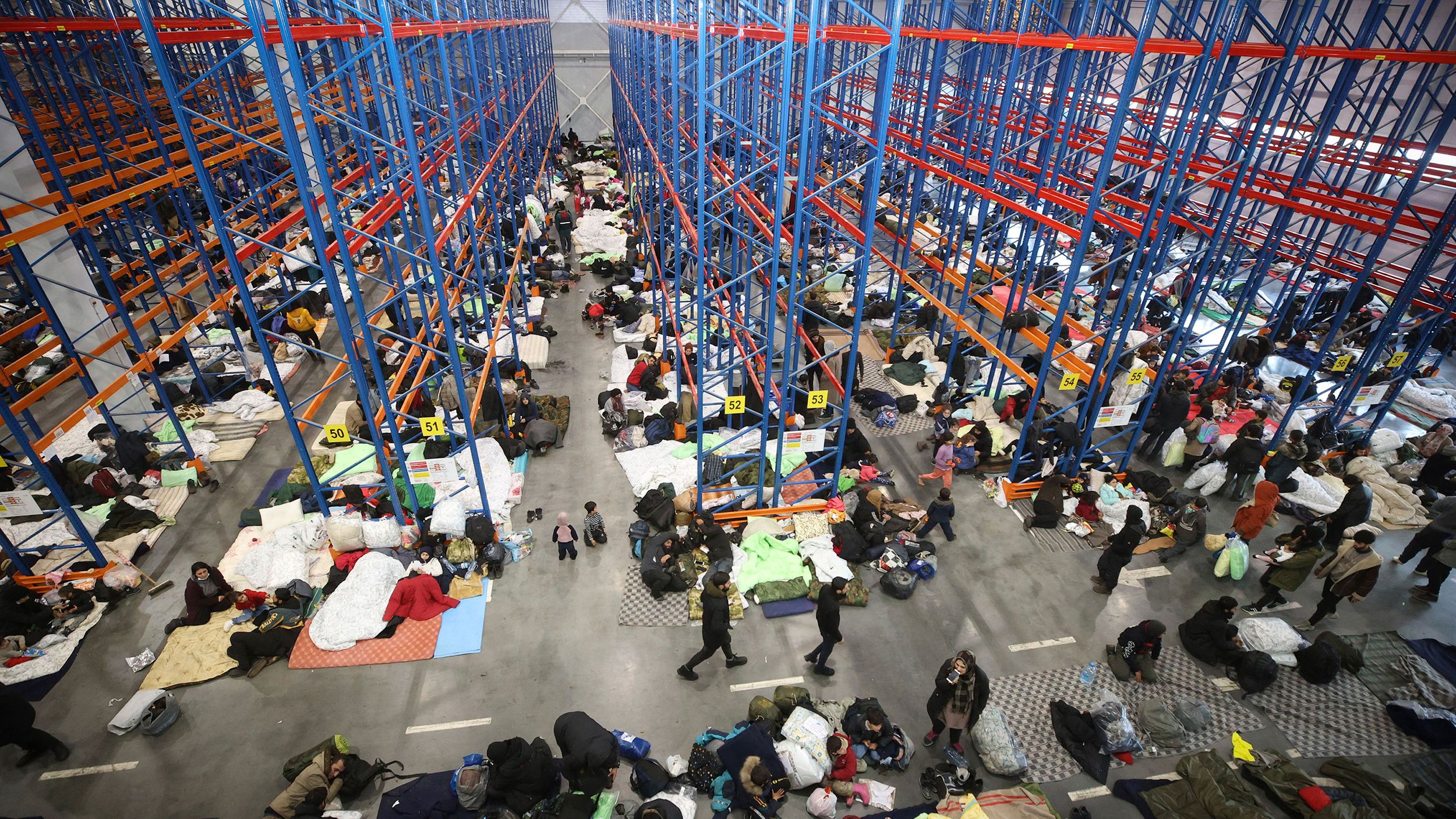 Migrants settle for the night on Thursday, November 18, in a warehouse near the Bruzgi-Kuźnica crossing serving as an ad hoc processing center.