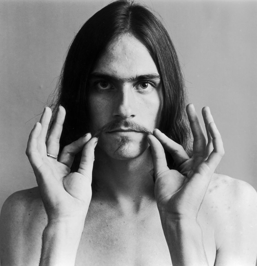 American folk musician James Taylor is pictured holding the ends of his mustache in this playful photo in 1969.