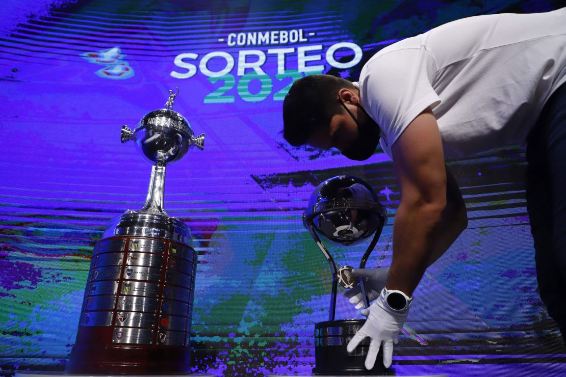 A worker displays the Copa Libertadores (L) and Copa Sudamericana trophies in Luque, Paraguay, on April 9, 2021. 