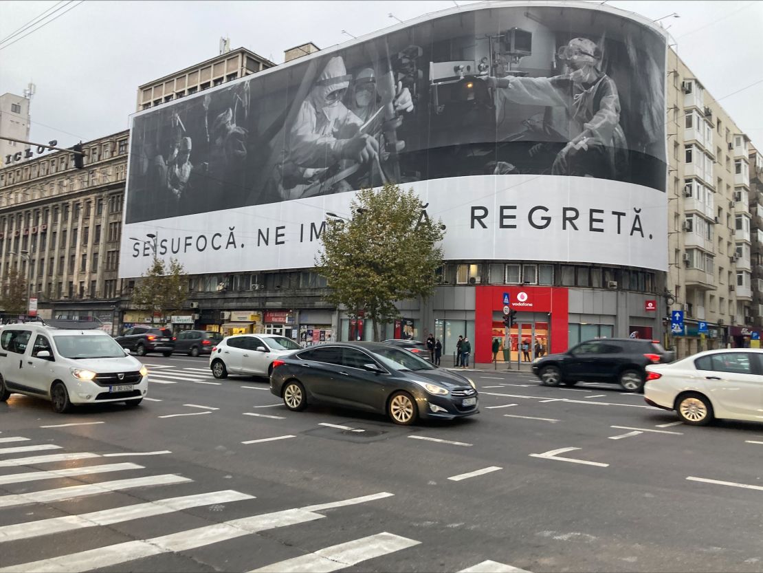 A banner in Bucharest shows medics working on Covid-19 patients with this message: "They're suffocating. They're begging us. They're regretting."