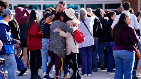 Edgar James, front center, battles with tears as he hugs his daughter, Mia, front right, and his wife, Olga Aguirre, front left, as they are reunited outside Hinkley High School in Aurora, Colo., on Friday, Nov. 19, 2021. Three people were shot Friday in the parking lot of the school, police said. (Philip B. Poston/Sentinel Colorado via AP)