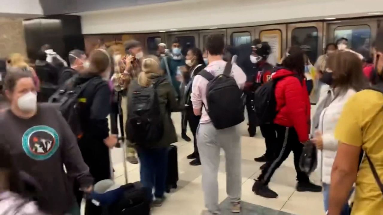 Travelers stand inside the Atlanta airport's domestic terminal after an accidental weapon discharge caused chaos and panic Saturday, November 20, 2021.