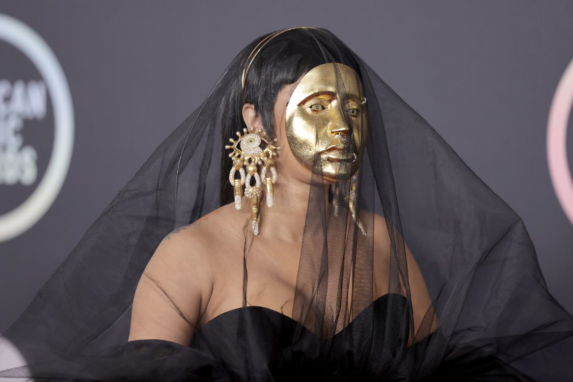 Rapper Cardi B put her best fashion foot forward on the red carpet, donning a black Schiaparelli gown and veil. She covered her face with a surreal golden mask and accessorized with statement earrings. 
