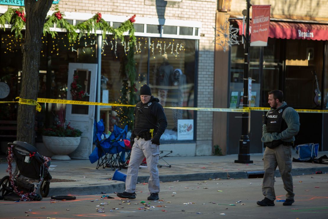 Police canvas debris left following a driver plowing into a Christmas parade on November 22, 2021, in downtown Waukesha, Wisconsin, killing six and injuring dozens.