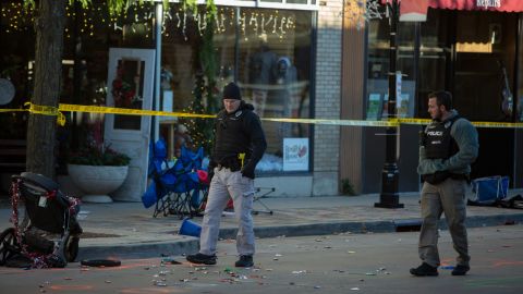 Police canvas debris left following a driver plowing into a Christmas parade on November 22, 2021, in downtown Waukesha, Wisconsin, killing six and injuring dozens.