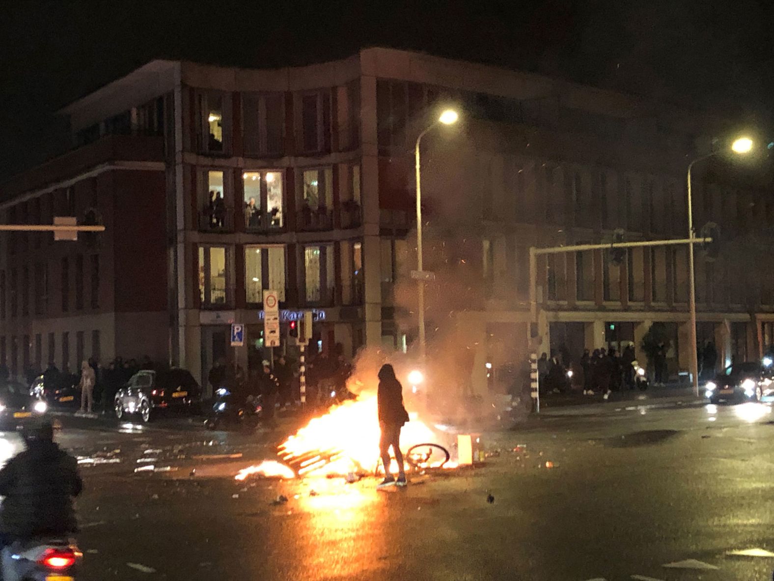 A man walks in front of a fire that was started in a street in The Hague, Netherlands, on Saturday. Rioting broke out over the Dutch government's new coronavirus measures. 